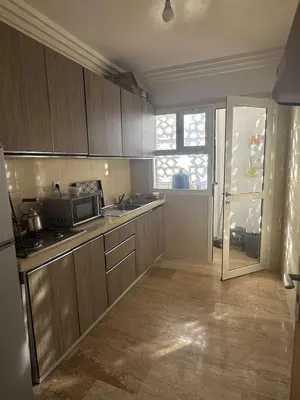 a kitchen with wooden cabinets and a microwave at Rabat en face de océan in Rabat