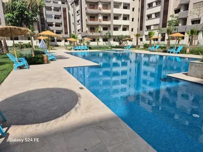 a large swimming pool with blue chairs and umbrellas at Aeroperla Prestige Casablanca Airport in Nouaseur