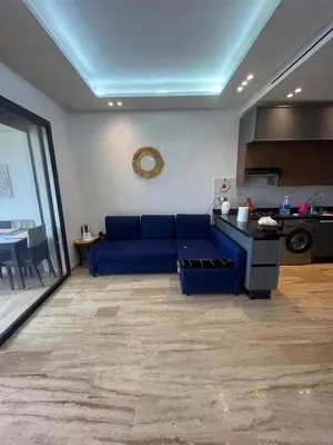 a living room with a blue couch and a kitchen at Relaxing Apartment Oceanic Sidi Rahal in Sidi Rahal