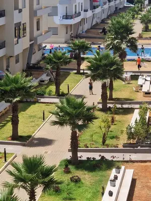 a view of a park with palm trees and a building at Sable d'or in O Ben Slimane