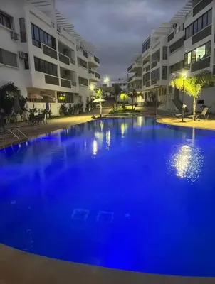 a large blue swimming pool in front of a building at Résidence oasis beach mansouriah in Mohammedia