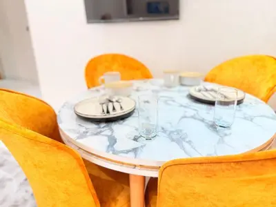 a dining room table with yellow chairs and a table with plates and glasses at Bright Cosy Apartment By Mohamed V Stadium in Casablanca