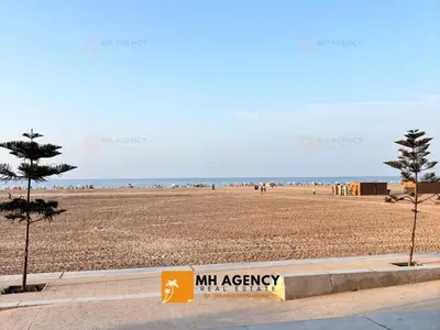 a view of the beach with a m apt agency sign at Oliveraie - Villa Benslimane in O Ben Slimane