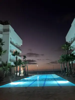 a building with a swimming pool at night at Cosy 2 chambres - Clim & Parking in Casablanca
