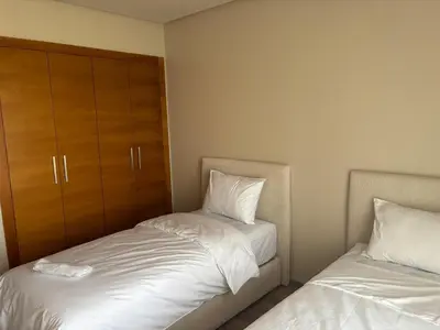 a bedroom with two beds with white sheets and a cabinet at Cosy 2 chambres - Clim & Parking in Casablanca