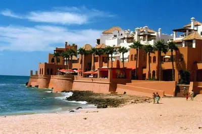 a large building on a beach with the ocean at Elegant Apartment with Pool & Moroccan Lounge in Bouznika
