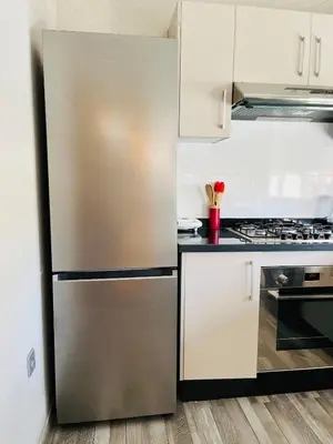 a stainless steel refrigerator in a kitchen with white cabinets at Studio 1 Min Beach - Pool - Air conditioning - Fiber in Mohammedia