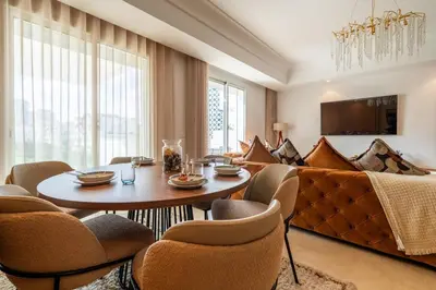 a living room with a table and a couch at Elegant Family Unit with Pool & Gym Casa Finance City m2a in Casablanca