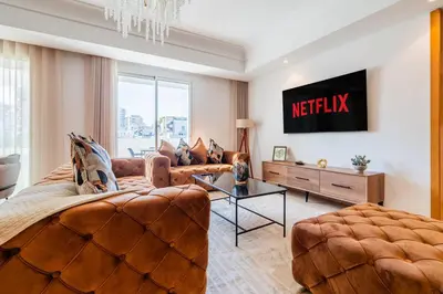 a living room with a couch and a tv at Elegant Family Unit with Pool & Gym Casa Finance City m2a in Casablanca