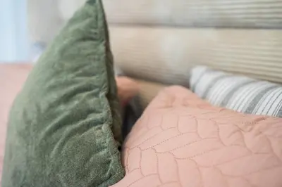 a green pillow sitting on top of a bed at Elegant Family Unit with Pool & Gym Casa Finance City m2a in Casablanca