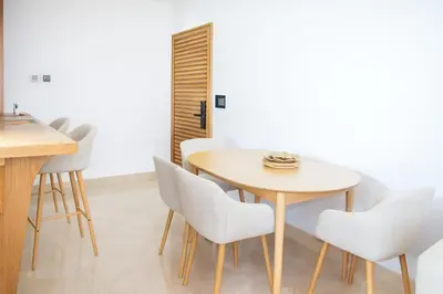 a dining room with a wooden table and white chairs at Kridarek - Appartement chic et cosy à Casa Finance City in Casablanca