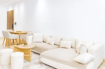 a living room with a white couch and a table at Kridarek - Appartement chic et cosy à Casa Finance City in Casablanca