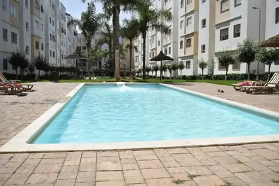 a large swimming pool in a courtyard with buildings at Kridarek - Bel appartement avec piscine à Dar Bouazza in Tamaris