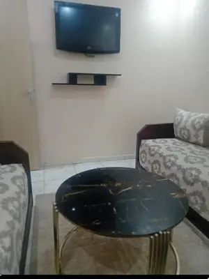 a living room with a table and a couch and a tv at Appartement moderne et confortable proche plages in Casablanca