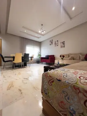 a living room with a bed and a table and chairs at Family Apartment à Jnane California Confort & Proximité in Casablanca