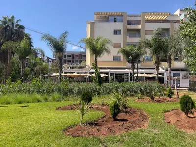 a garden with palm trees in front of a building at Family Apartment à Jnane California Confort & Proximité in Casablanca