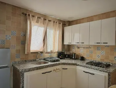 a kitchen with white cabinets and a sink and a window at Appartement arome in Rabat