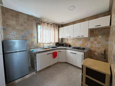 a kitchen with white cabinets and a stainless steel refrigerator at Appartement arome in Rabat
