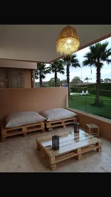 a room with two beds and a table and a chandelier at Appartement vue à la mer Bouznika in Sidi el Haj Bou Derbala