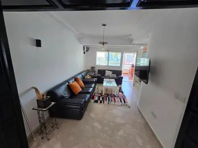 a living room with a black leather couch and a tv at Ideal apartment for business trips in Casablanca
