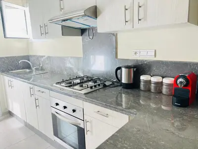 a kitchen with white cabinets and a stove top oven at Fal azure in Bouznika