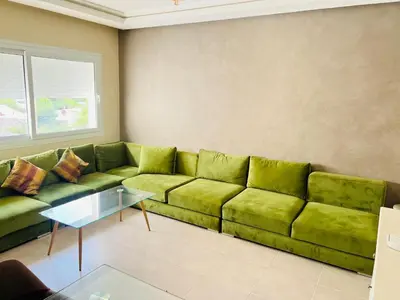a living room with a green couch and a table at Fal azure in Bouznika