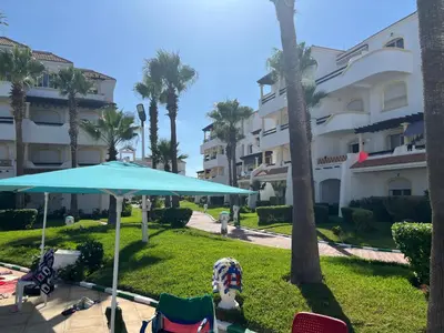 a patio with chairs and an umbrella in front of a building at Garden beach 2 in Sidi Rahal