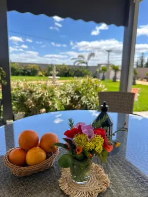 a table with a vase of oranges and a basket of flowers at la ferme du bonheur in Aïn el Apuda