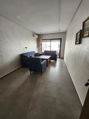 a living room with a blue couch and a table at Apparemment de détente in Mansouria