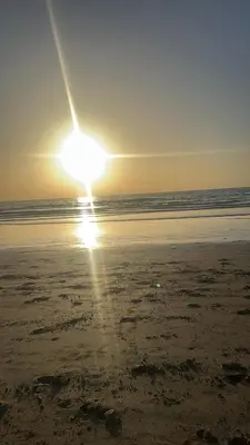 a sun setting on a beach with the ocean at chic & cozy Apartment, Parc Serenity in Mohammedia