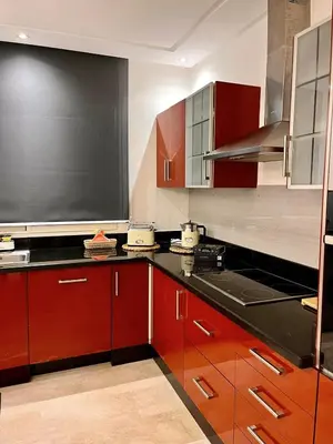 a kitchen with red cabinets and a black counter top at Chic, well-equipped apartment in a perfect location in Temara