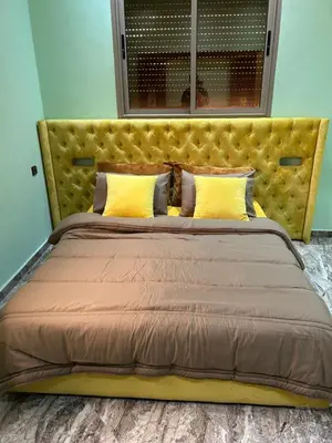 a large bed with a yellow headboard in a room at Appartment calme a Ain Aouda in Aïn el Apuda