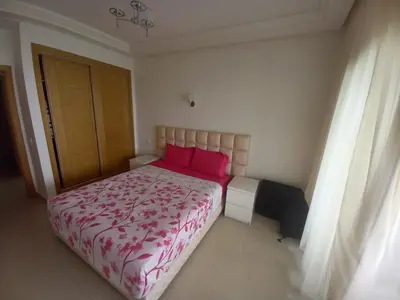 a bedroom with a large bed with pink pillows at Résidence balnéaire - Piscine Plage et Diverses in Sidi Rahal