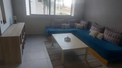 a living room with a blue couch and a table at La vie de vacances fal azur in Bouznika