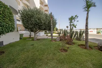 a yard in front of a building with trees and plants at Calme & Cocon Apartment Near Airport in Nouaceur