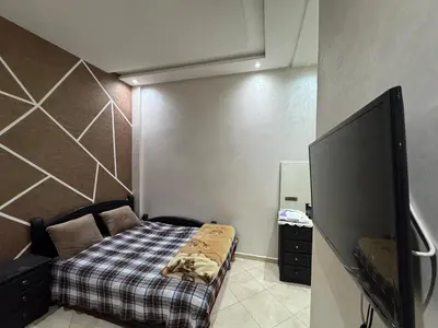 a small bedroom with a bed and a flat screen tv at 3 bedroom apartment with living room and terrace 90metre in El Harhoura