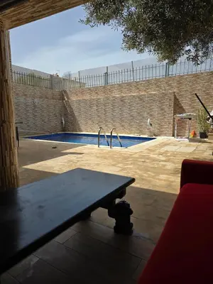 a wooden bench sitting in front of a swimming pool at Floor Villa rent in El Harhoura