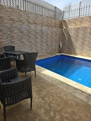 a swimming pool with chairs and a table next to it at Appartement villa in Temara