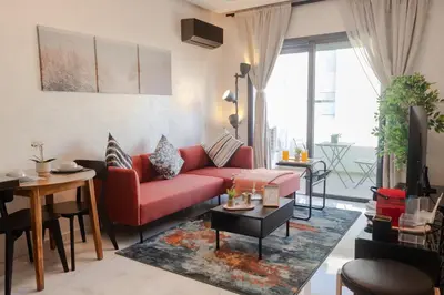 a living room with a red couch and a table at VIVASTAY Casablanca - Ocean Park Sunset Escape beach front with swimming pool in Aïn Harrouda