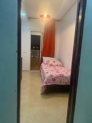 a small bedroom with a bed with a pink blanket at Appartement Sidi Rehal beach in Sidi Rahal