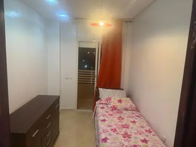 a small bedroom with a bed and a desk at Appartement Sidi Rehal beach in Sidi Rahal