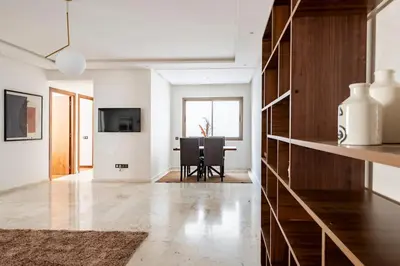 a living room with a table and a dining room at Appartement neuf et moderne à l'Agdal, 2 chambres in Rabat