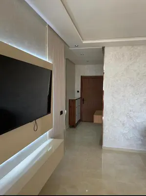 a living room with a large flat screen tv on a wall at Résidence Beach Land El Mansouria in Mohammedia