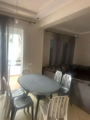 a table and chairs in a living room with a couch at New and cosy appt for rent in Sidi Rahal