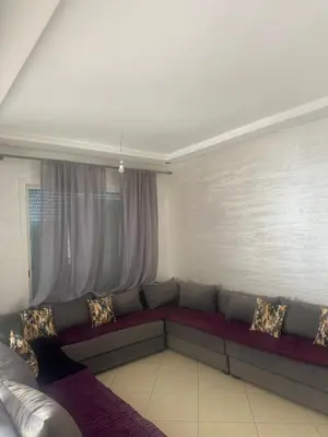 a living room with a long couch in front of a window at New and cosy appt for rent in Sidi Rahal