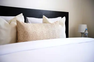 a white bed with a black head board and pillows at Cozy Apartment in the Heart of Bouznika in Bouznika