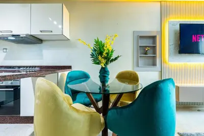 a kitchen with blue chairs and a table with a vase of flowers at Appartement Élégant au Cœur de Central Park in Mohammedia