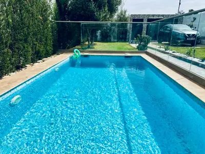 a swimming pool with blue water in a backyard at Belle villa spacieuse et calme avec piscine à 7min de la plage en voiture in Tamaris