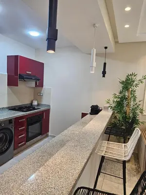 a kitchen with a counter and some chairs in it at Appartement El Mansouria Séjour Luxueux Plage & vue Piscine in Mansouria