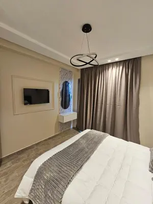 a bedroom with a large bed and a television at Appartement El Mansouria Séjour Luxueux Plage & vue Piscine in Mansouria